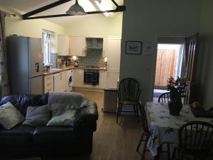 a living room with a couch and a table and a kitchen at Lemondrop Cottage in Southburgh