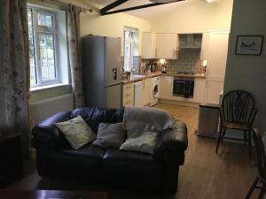 a living room with a couch and a kitchen at Lemondrop Cottage in Southburgh