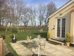 a patio with chairs and a table in a yard at Lemondrop Cottage in Southburgh