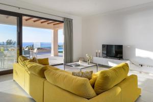 un divano giallo in soggiorno con televisore di Villa Sa Rota Luxury Sea Views a San Antonio