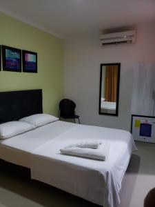 1 dormitorio con 1 cama grande con sábanas blancas en Hotel Rodadero Real, en Santa Marta
