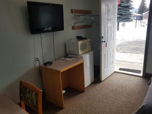 a room with a television and a desk at Anchor Riverfront Motel in Sicamous