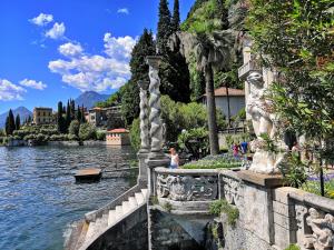 Near Villa Monastero and Castello di Vezio في فارنا: امرأة تقف على جسر فوق قطعة ماء