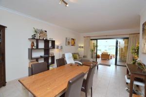 a dining room and living room with a wooden table and chairs at CONDOMINIO LOS OLIVOS DEL GOLF in Faro