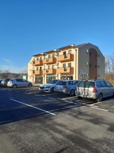 un estacionamiento con autos estacionados frente a un edificio en Apartman Centar, en Veliko Gradiste