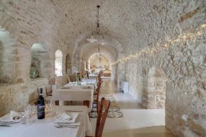 un restaurante con mesas blancas y sillas en una pared de piedra en Masseria Storica Pilapalucci, en Toritto