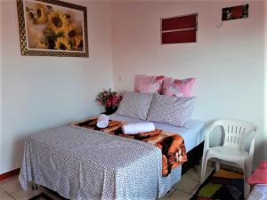1 dormitorio con 1 cama con manta y silla en Aconchego - Família Mangas Monteiro, en Macapá