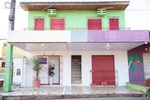 un edificio colorato con porte rosse e balcone di Aconchego - Família Mangas Monteiro a Macapá