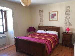 ein Schlafzimmer mit einem großen Bett mit einer lila Decke in der Unterkunft Le Milieu Chai, Chateau de Charras in Charras