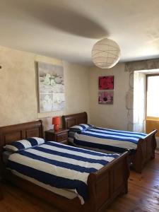 1 Schlafzimmer mit 2 Betten mit blauen und weißen Streifen in der Unterkunft Le Milieu Chai, Chateau de Charras in Charras