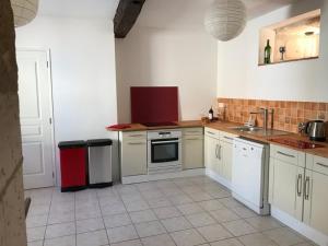 eine Küche mit weißen Schränken und einem roten Kühlschrank in der Unterkunft Le Milieu Chai, Chateau de Charras in Charras