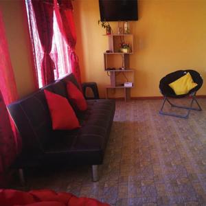Cabaña Oasis de Pica في بيكا: غرفة معيشة مع أريكة سوداء ووسائد حمراء