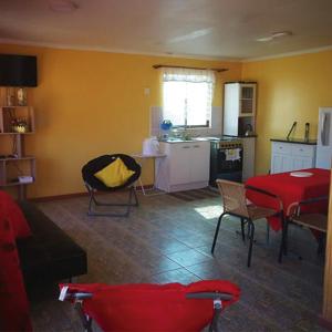 a living room with a red table and a kitchen at Cabaña Oasis de Pica in Pica