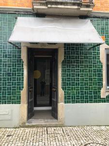 un edificio con paredes de azulejos verdes y una puerta en Feel at Home Guest House en Ovar