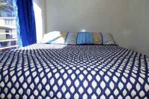 a bed with a blue and white comforter and a window at Hotel La Avenida in Choachí