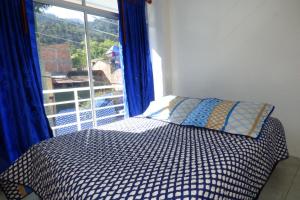 a bedroom with a bed and a large window at Hotel La Avenida in Choachí