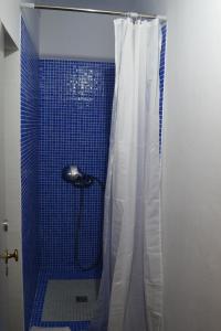 y baño con ducha azul y cortina de ducha. en Ria Guest House, en Alvor