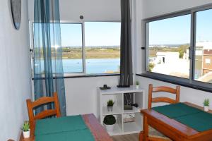 a dining room with a table and chairs and windows at Ria Guest House in Alvor