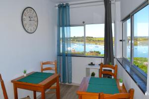 a dining room with a table and chairs and a clock at Ria Guest House in Alvor