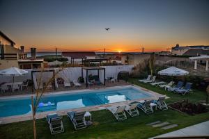 a backyard with a swimming pool and chairs and the sunset at Cara Colomba in La Paloma