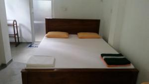 um quarto com uma cama grande com lençóis brancos e almofadas laranja em Disa Residence em Galle