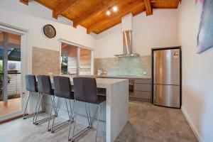 a kitchen with a counter with chairs and a refrigerator at Port Central No 3 in Port Campbell