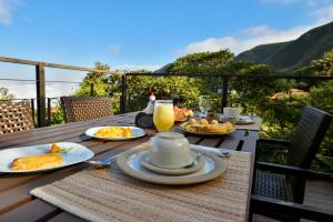 a table with plates of food and a glass of orange juice at Pousada Estalagem do Mirante in Brumadinho