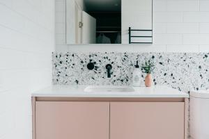 cocina blanca con lavabo y espejo en Laneway Apartments - Orientem en Port Fairy