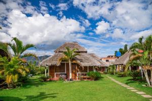 un complejo con palmeras y techo de hierba en Bungalows El Palmiche, en Satipo