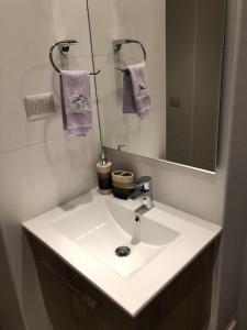 La salle de bains est pourvue d'un lavabo blanc et d'un miroir. dans l'établissement Departamento Pucón Andino, à Pucón