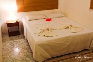 um quarto com uma cama com lençóis brancos e flores em Pousada Dois Irmãos em Fernando de Noronha
