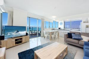 a living room with a couch and a tv and a kitchen at Beachfront Towers in Maroochydore