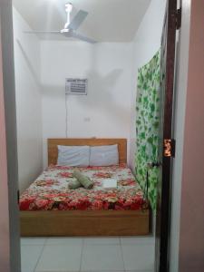 a small bedroom with a bed with a floral bedspread at Lapyahan Guest House in Siquijor