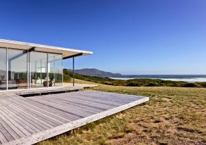 a house on the beach with a wooden deck at Cloudy Bay Beach House in South Bruny