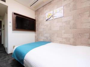 a bedroom with a bed and a flat screen tv at Central Hotel Okayama in Okayama