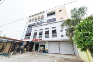 a white building with a parking lot in front of it at RedDoorz @ San Jose Tagbak Jaro Iloilo in Iloilo City