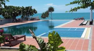 Khanom Beach Residence Rental Condo في خانوم: حمام سباحة مع مقاعد والمحيط في الخلفية