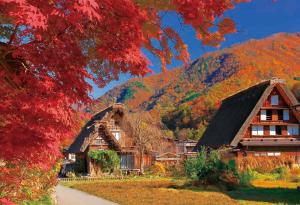 una casa con techo de paja en las montañas en Home Sharing Guest House Don en Takayama