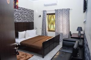 ein Schlafzimmer mit einem Bett, einem Sofa und einem Fenster in der Unterkunft 3A's Guest House in Akosombo