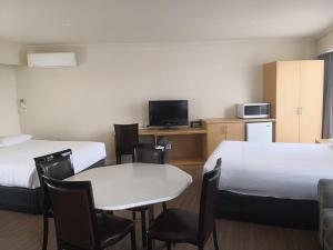 丹德農的住宿－丹德農汽車旅館，酒店客房带两张床和一张桌子以及椅子。