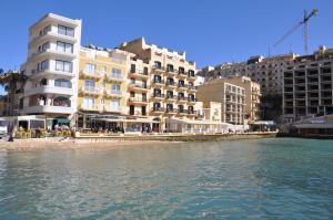 a group of buildings next to a body of water at Superior Xlendi Lungomare Apartment in Xlendi