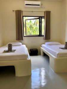 two beds in a room with a window at Parrots Boutique Resort in San Vicente