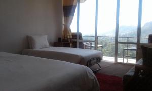 een hotelkamer met 2 bedden en een groot raam bij woods hut in Nuwara Eliya