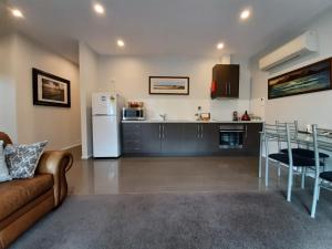 eine Küche und ein Wohnzimmer mit einem Sofa und einem Kühlschrank in der Unterkunft Spring Beach Garden Retreat in Spring Beach
