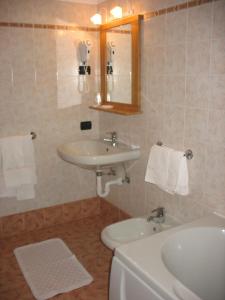 a bathroom with a sink and a toilet and a mirror at Hotel Cevedale in Santa Caterina Valfurva