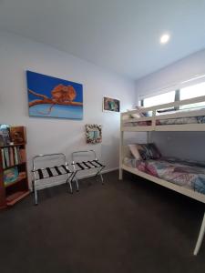 a room with two bunk beds and a book shelf at Spring Beach Garden Retreat in Spring Beach