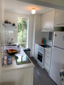 a kitchen with white cabinets and a white refrigerator at Relax On Bingham in Goolwa +9 photos