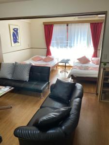 a living room with a leather couch and two beds at Laforet Tokaichi in Hiroshima