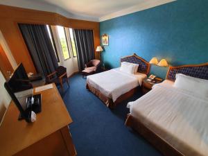 a hotel room with two beds and a desk at Parkview Hotel in Kampong Jerudong