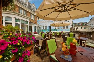 un patio esterno con tavoli, sedie e fiori di Best Western Moores Central Hotel a St Peter Port